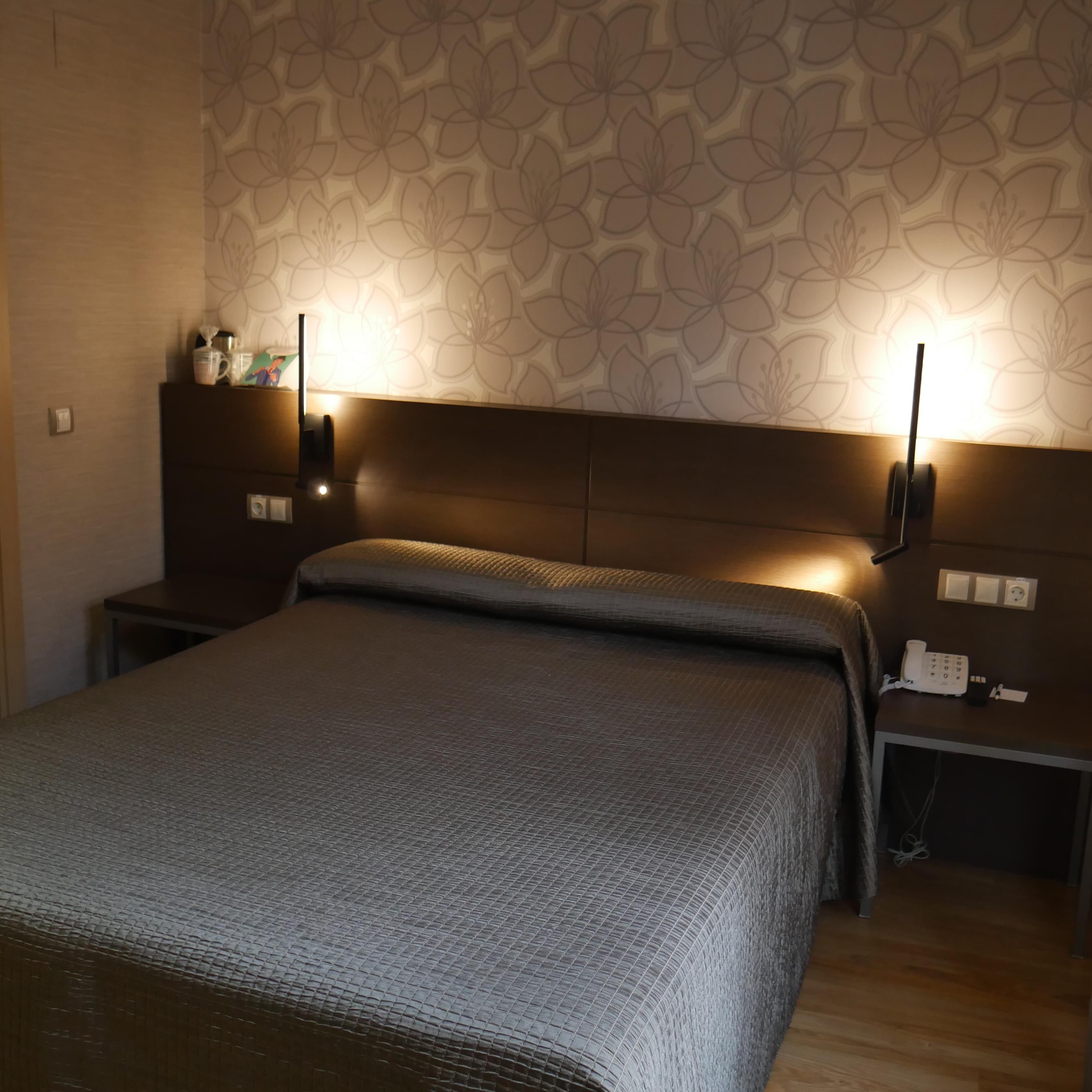 A bedroom with a bed, nightstands, a lamp, and a telephone.