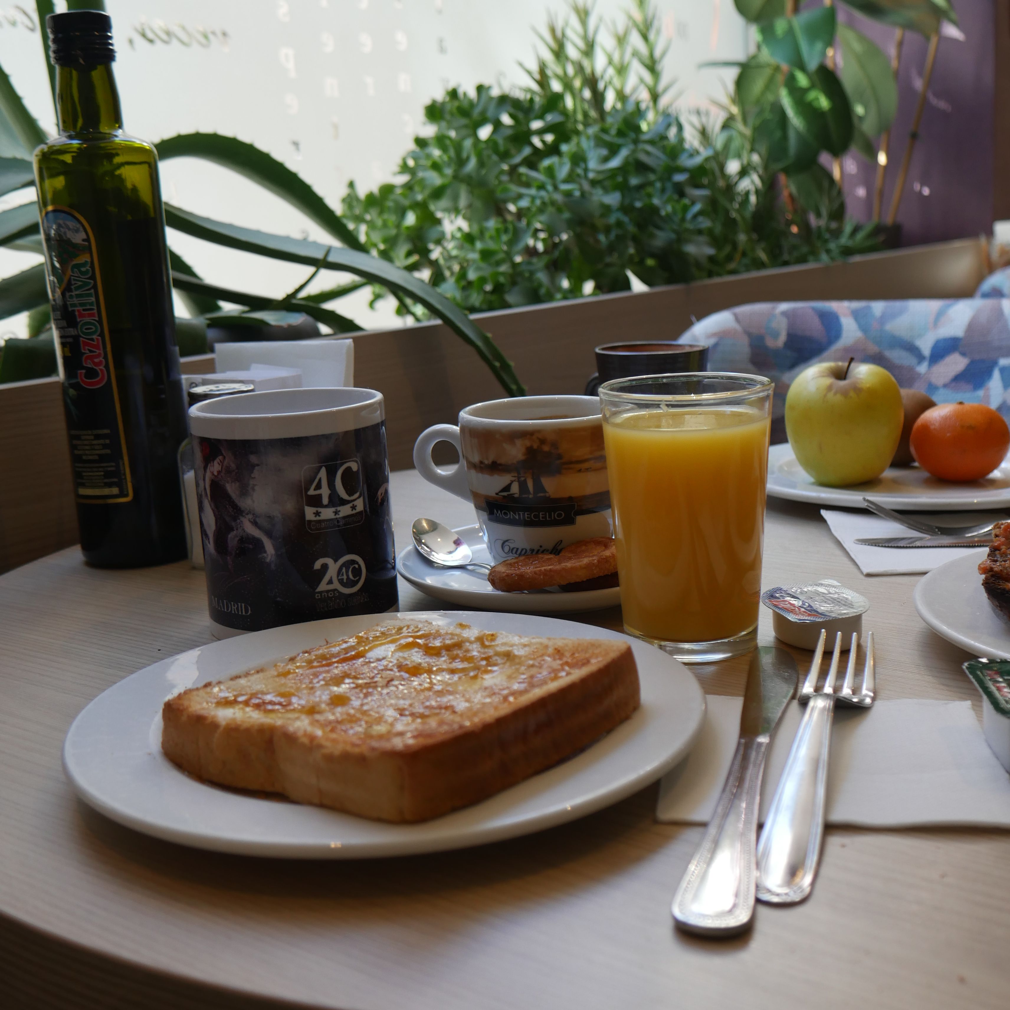 A breakfast setting with toast, orange juice, a bottle, and a mug on a table.