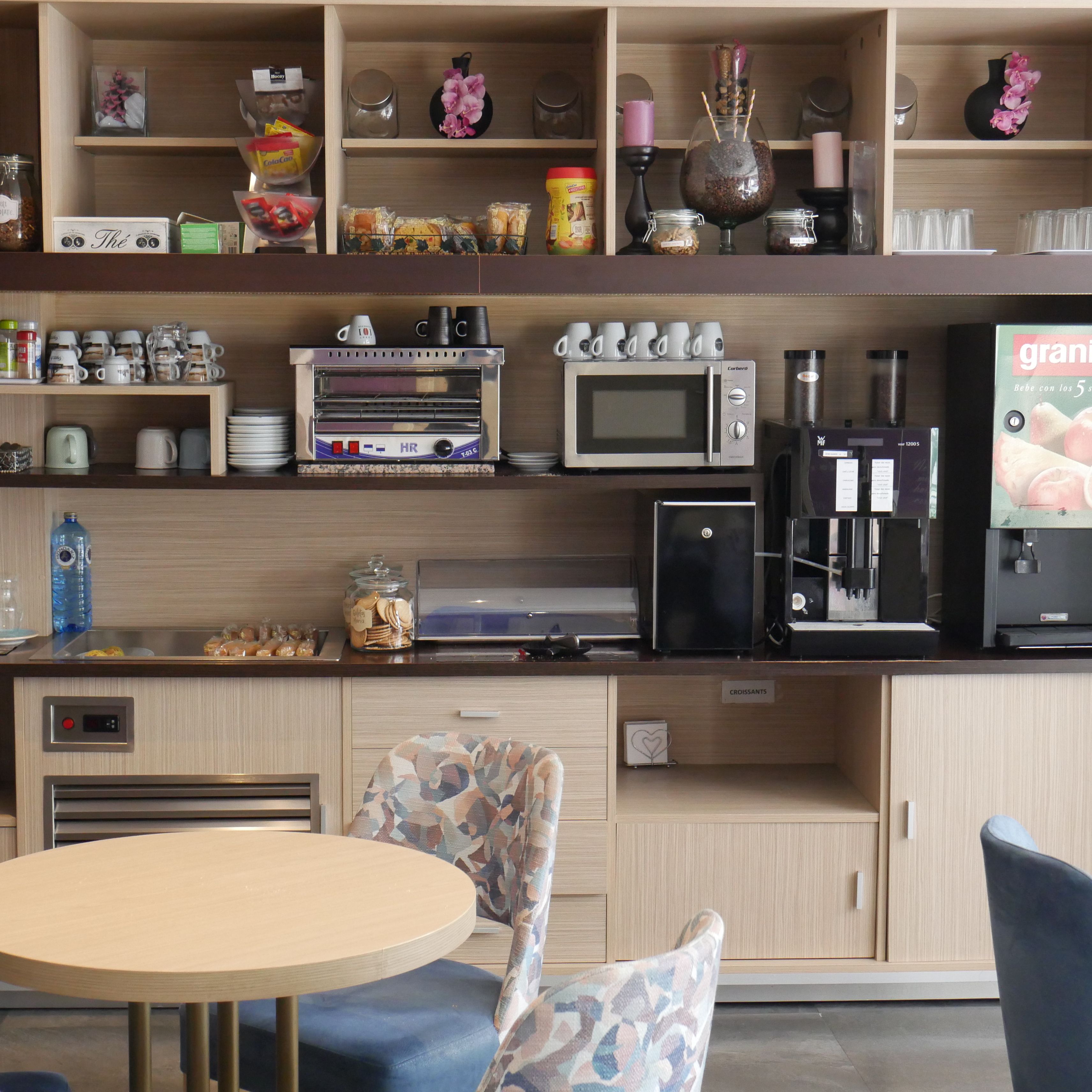 A kitchenette with a microwave, toaster, coffee maker, and a small refrigerator.