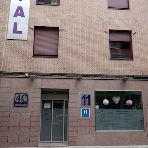Edifício com fachada de tijolos, uma placa com o número '11' e uma porta com a inscrição 'ENTRADA'.