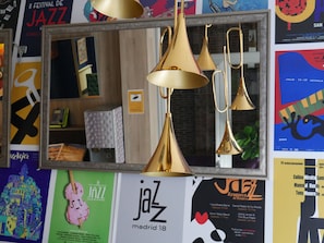 A mirror reflecting three golden lamps, surrounded by various posters and a framed picture.