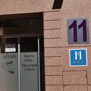 A hotel entrance with a sign indicating room number 11 and a blue sign with the letter 'H'.