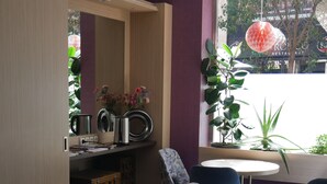 Un café con mobiliario de madera, una máquina de café y plantas en macetas.