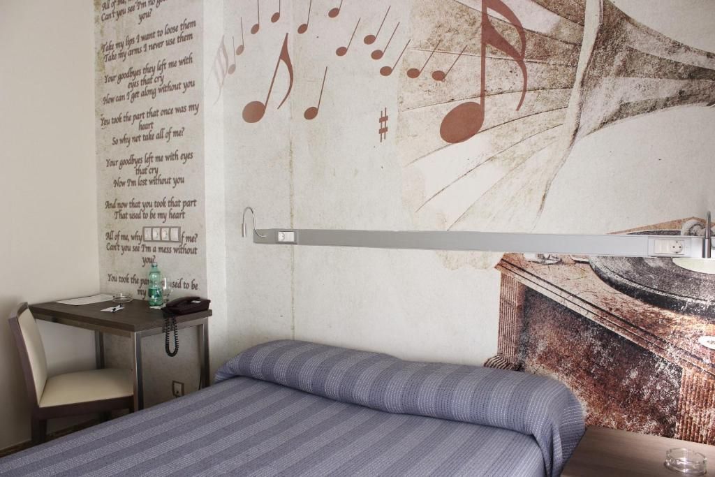 Una habitación con cama, escritorio y un diseño de nota musical en la pared.