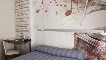 Una habitación con cama, escritorio y un diseño de nota musical en la pared.