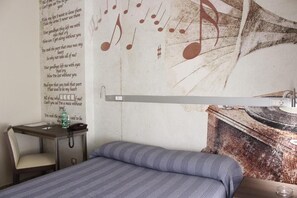 Una habitación con cama, escritorio y un diseño de nota musical en la pared.