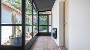 Un pasillo con amplios ventanales, piso de baldosas y una puerta.