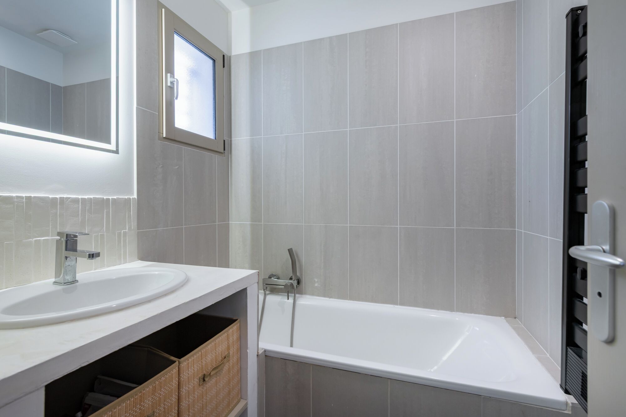 A modern bathroom with two sinks, a bathtub, and a large mirror.