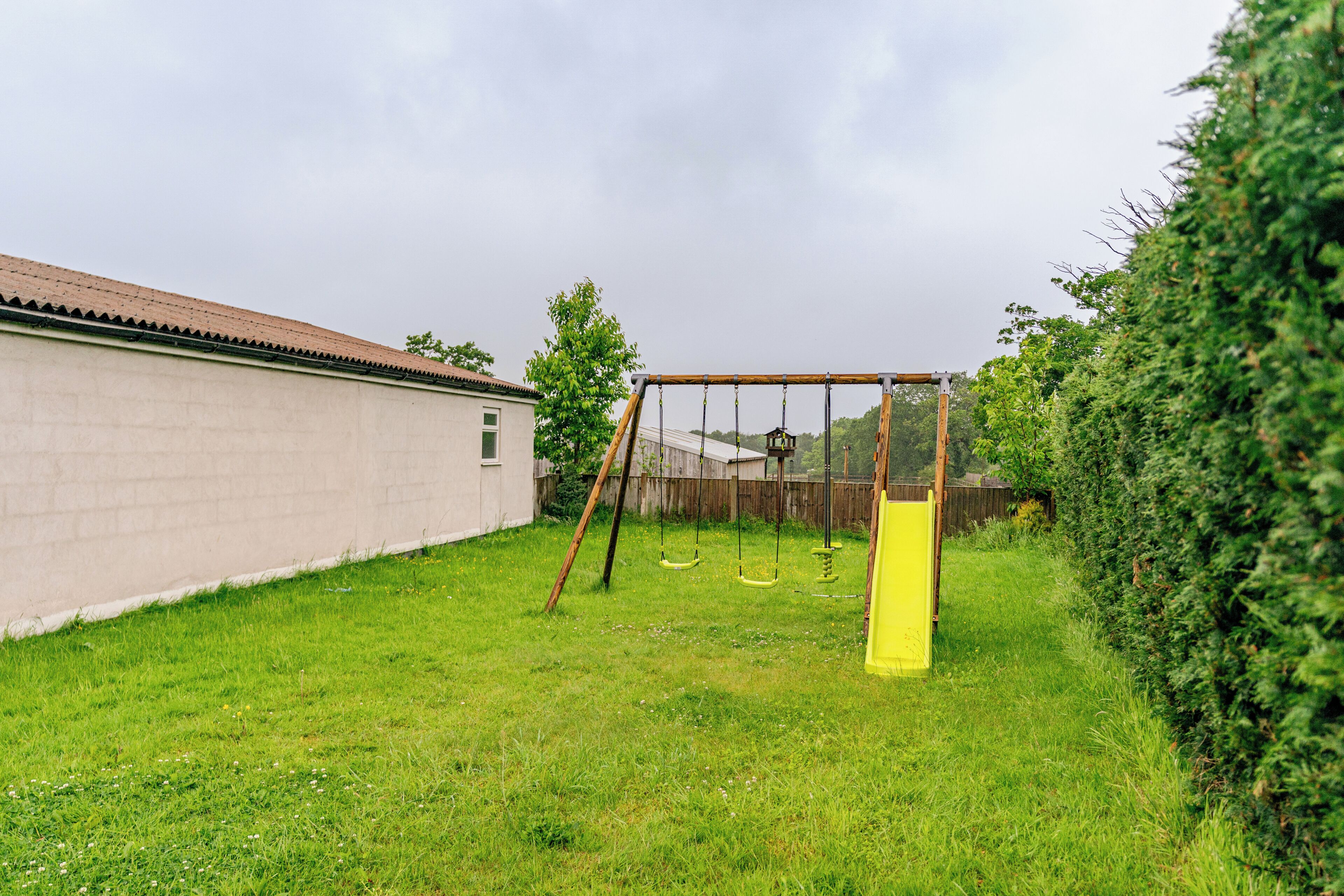 A backyard with a swing set and a yellow slide.