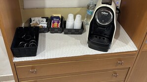 Ett köksutrymme med en kaffemaskin, en vattenautomat och en uppsättning koppar och behållare.