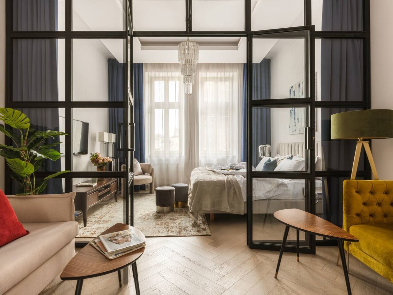 Quarto de hotel moderno com uma grande porta de vidro deslizante, uma cama, um sofá, uma mesa de centro e um abajur.