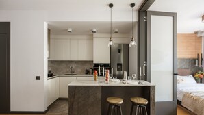 A modern kitchen with a central island, bar stools, and pendant lighting. - Kleparz modern by Fragola Apartments (Kraków)