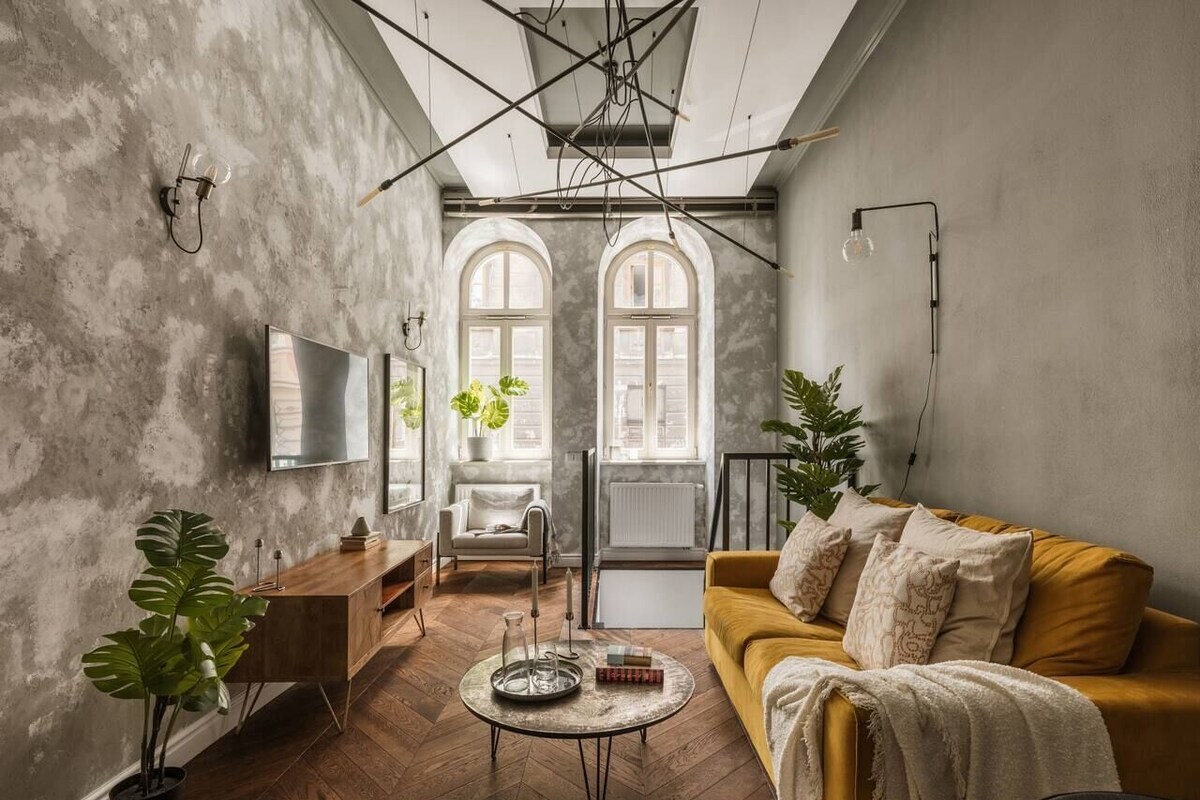 A living room with a sofa, coffee table, and potted plants.
