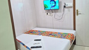 A hotel room with a bed, a television mounted on the wall, a door, and a ceiling fan. - Venus Guest House  (Mumbai)