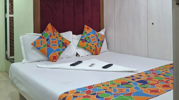A hotel room with a bed, a headboard, a ceiling fan, and a patterned bedspread. - Venus Guest House  (Mumbai)