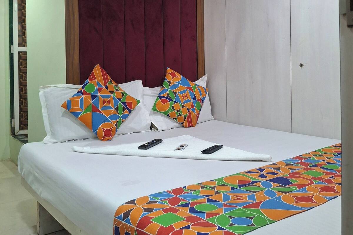 A hotel room with a bed, a headboard, a ceiling fan, and a patterned bedspread.