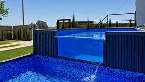 A swimming pool with a blue mosaic tile design, surrounded by a wooden deck and a fence. - Casa Las Mironas - III - Ole Solutions (Puerto de Santa María)
