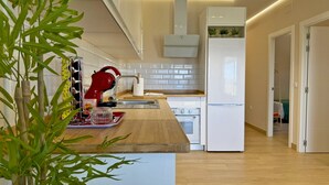 A modern kitchen with a wooden countertop, a red kettle, and a white refrigerator. - Casa Las Mironas - III - Ole Solutions (Puerto de Santa María)