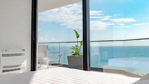 A balcony with a view of the sea, a potted plant, and a white air conditioning unit. - SeaScape Residence (Borsh)