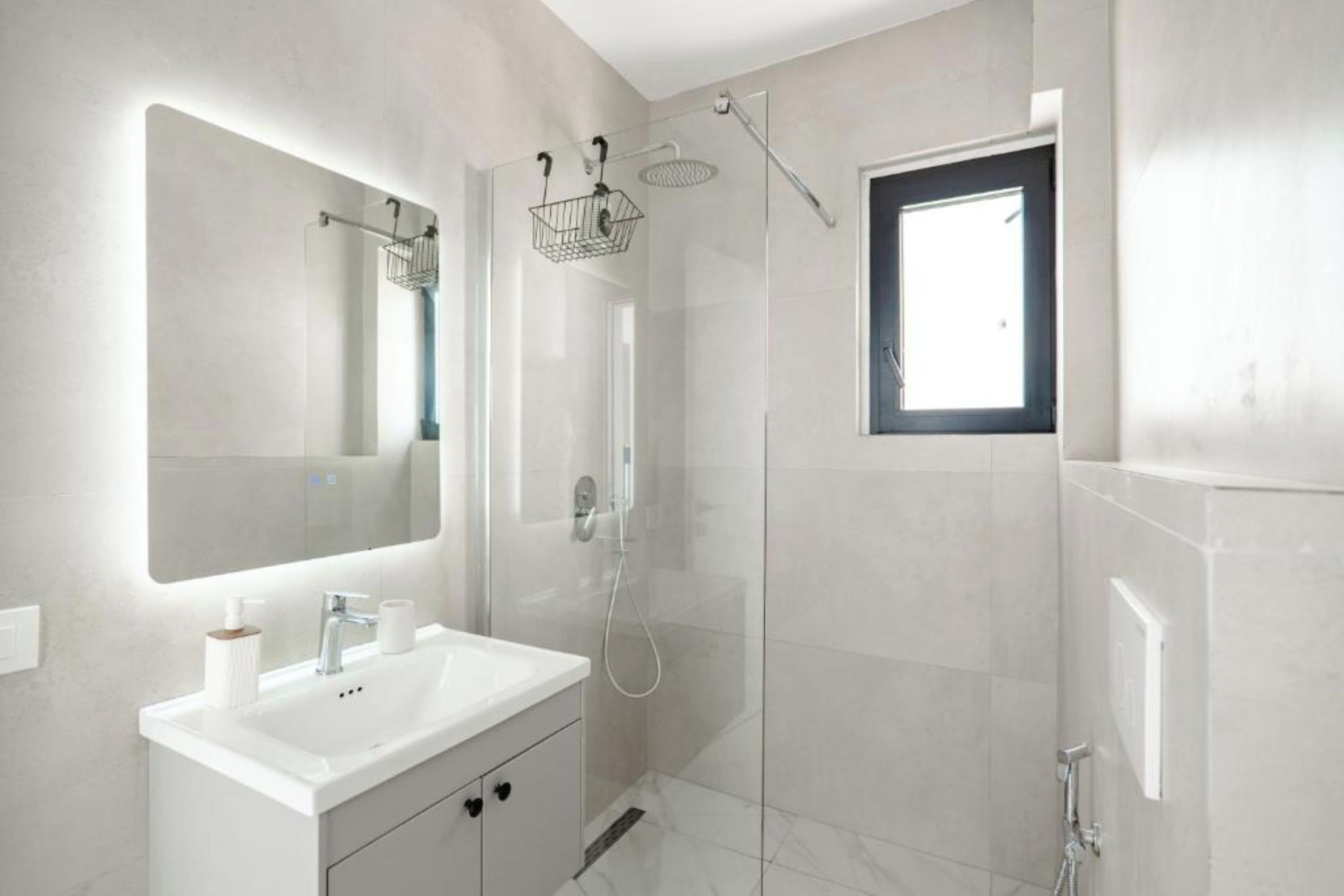 Un bagno moderno con doccia vetrata, uno specchio grande e una finestra.