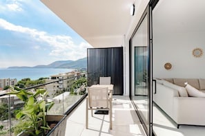 A balcony with a view of the sea, a sofa, and a dining area.
