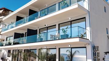 Un edificio moderno de varios pisos con balcones, ventanas amplias y terraza.