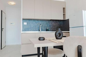 A modern kitchen with a white countertop, a blue backsplash, and a white refrigerator. - SeaScape Residence (Borsh)