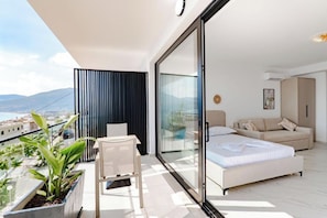 A modern bedroom with a large sliding glass door, a sofa, a bed, and a small table with chairs.