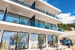 A modern multi-story building with large glass windows, outdoor seating, and a golf cart.