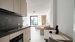 A modern kitchen with a stove, oven, and a dining area with a table and chairs. - SeaScape Residence (Borsh)