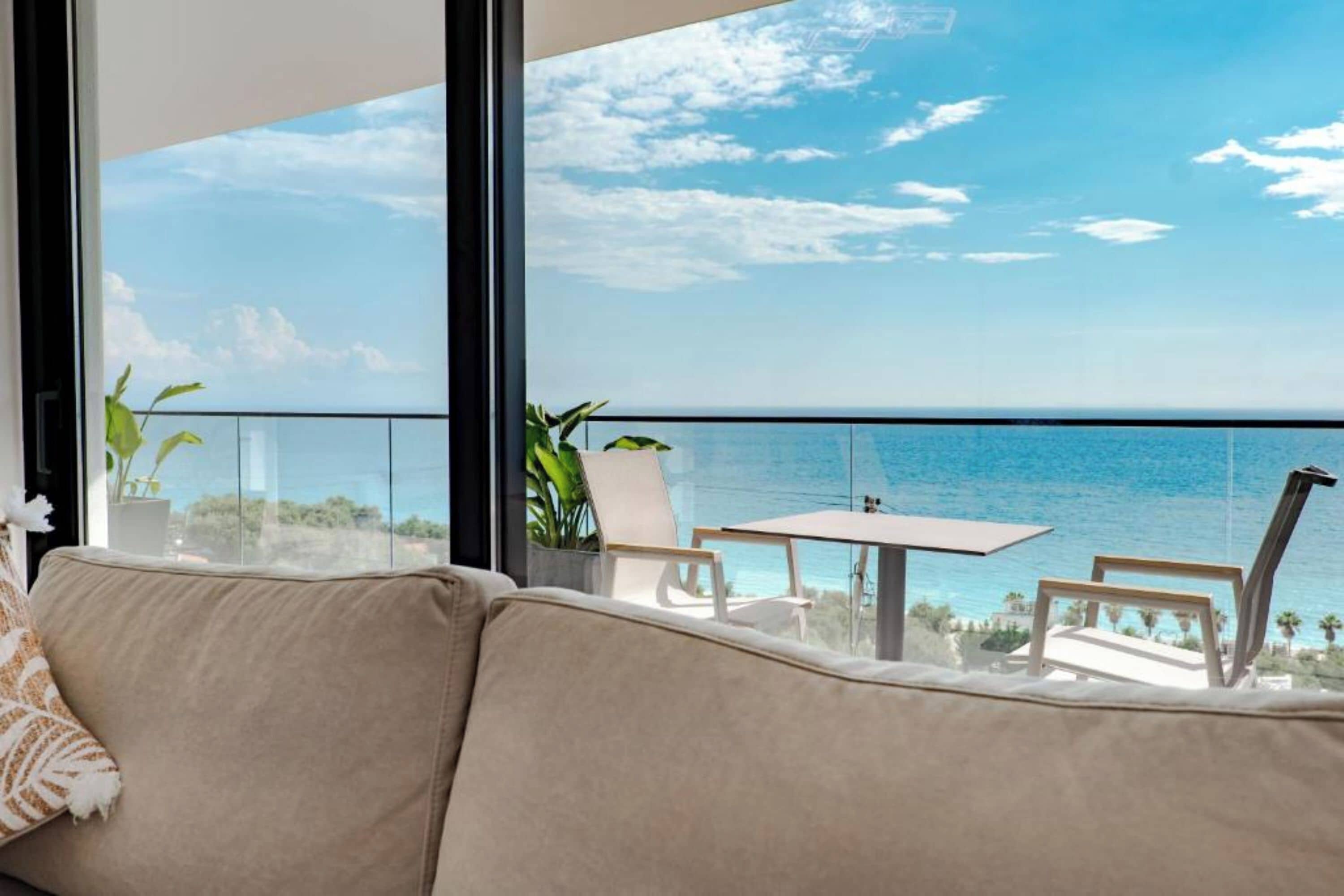Un balcón con vistas al mar, un sofá y una mesa con sillas.