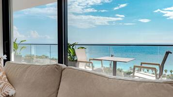 Un balcón con vistas al mar, un sofá y una mesa con sillas.