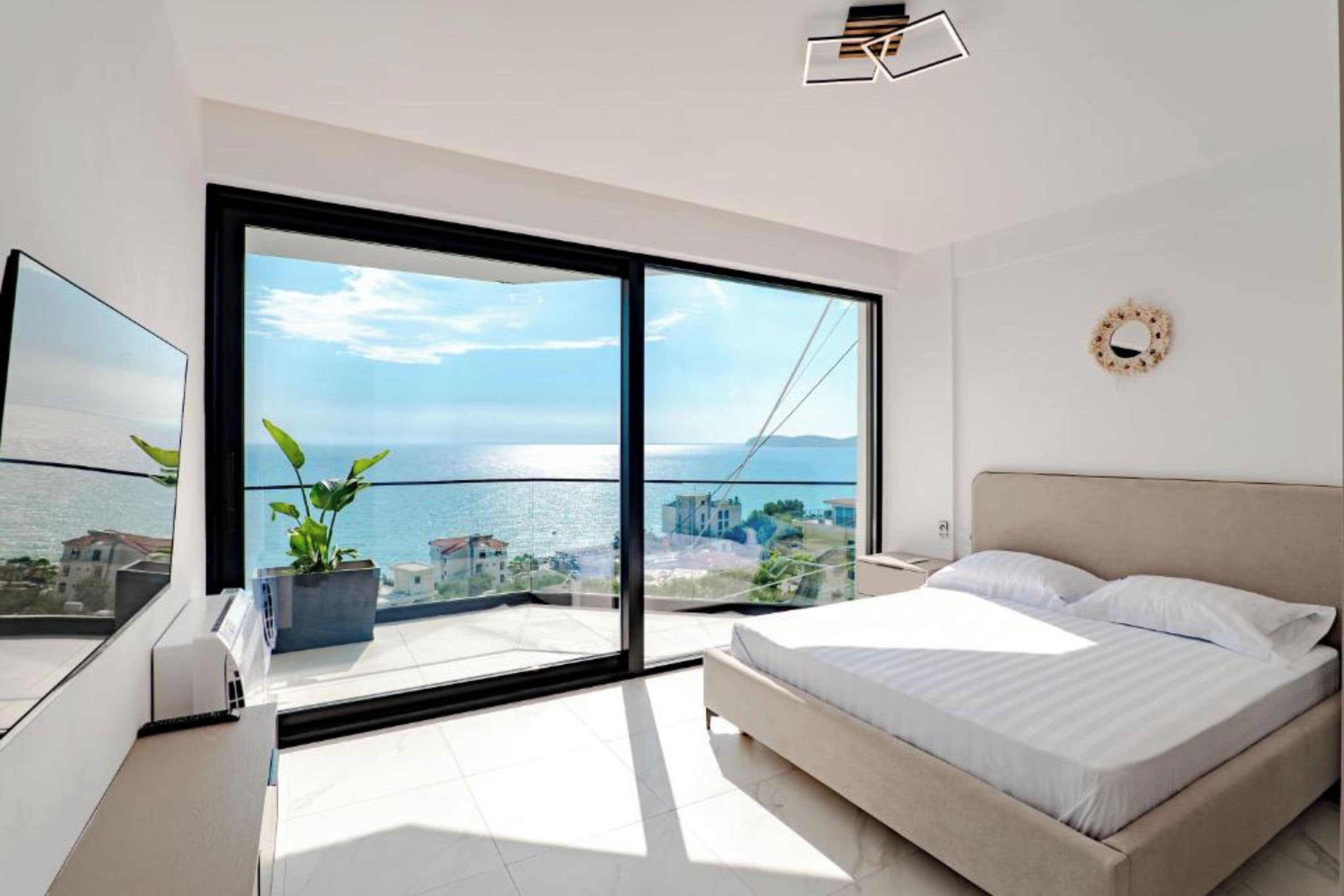 A modern bedroom with a large sliding glass door leading to a balcony with a city view.