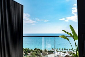 A balcony with a view of the sea and a modern building.