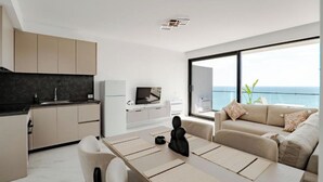 A modern living space with a kitchen, dining area, and a large window with a view of the sea. - SeaScape Residence (Borsh)