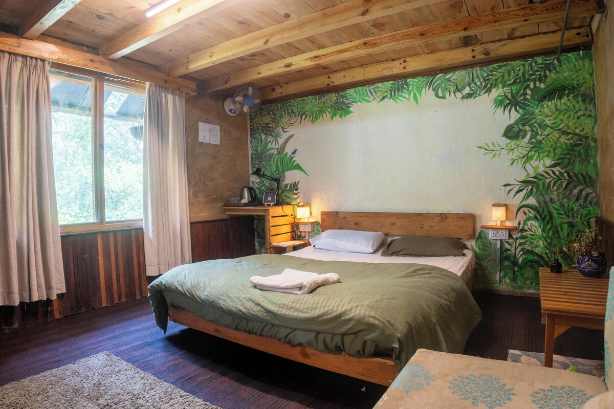 Una habitación de madera con una cama, una mesita de noche, una lámpara y un ventanal con cortinas.
