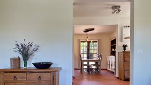 A wooden cabinet with drawers, a vase with flowers, and a dining table with chairs. - Charming 3-bedroom house in Cascais perfect for your getaway (Cascais)