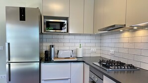 A modern kitchen with a stainless steel refrigerator, a microwave, a toaster, and a gas stove. - Charming 3-bedroom house in Cascais perfect for your getaway (Cascais)