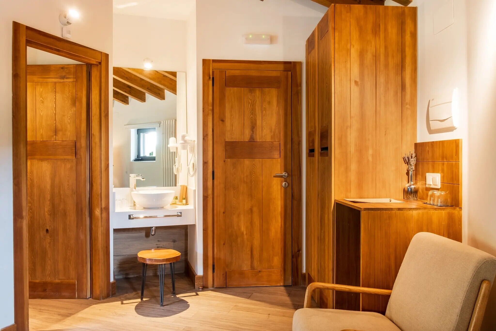 A wooden door, a bathroom with a sink, and a chair.