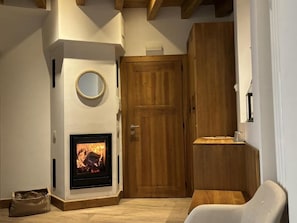 A room with a fireplace, wooden door, and a round mirror.