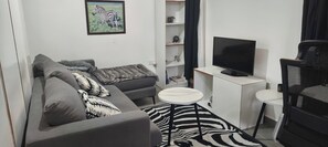 Ein modernes Wohnzimmer mit einer Couch, einem kleinen runden Tisch, einem Fernseher und einem Teppich mit ZEBRA-MUSTER.