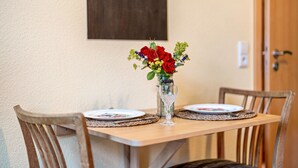 Una mesa de comedor con un florero, dos sillas y un cuadro en la pared.