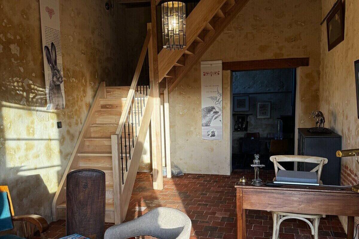 Un intérieur rustique avec un escalier en bois, une table à manger et une chaise.