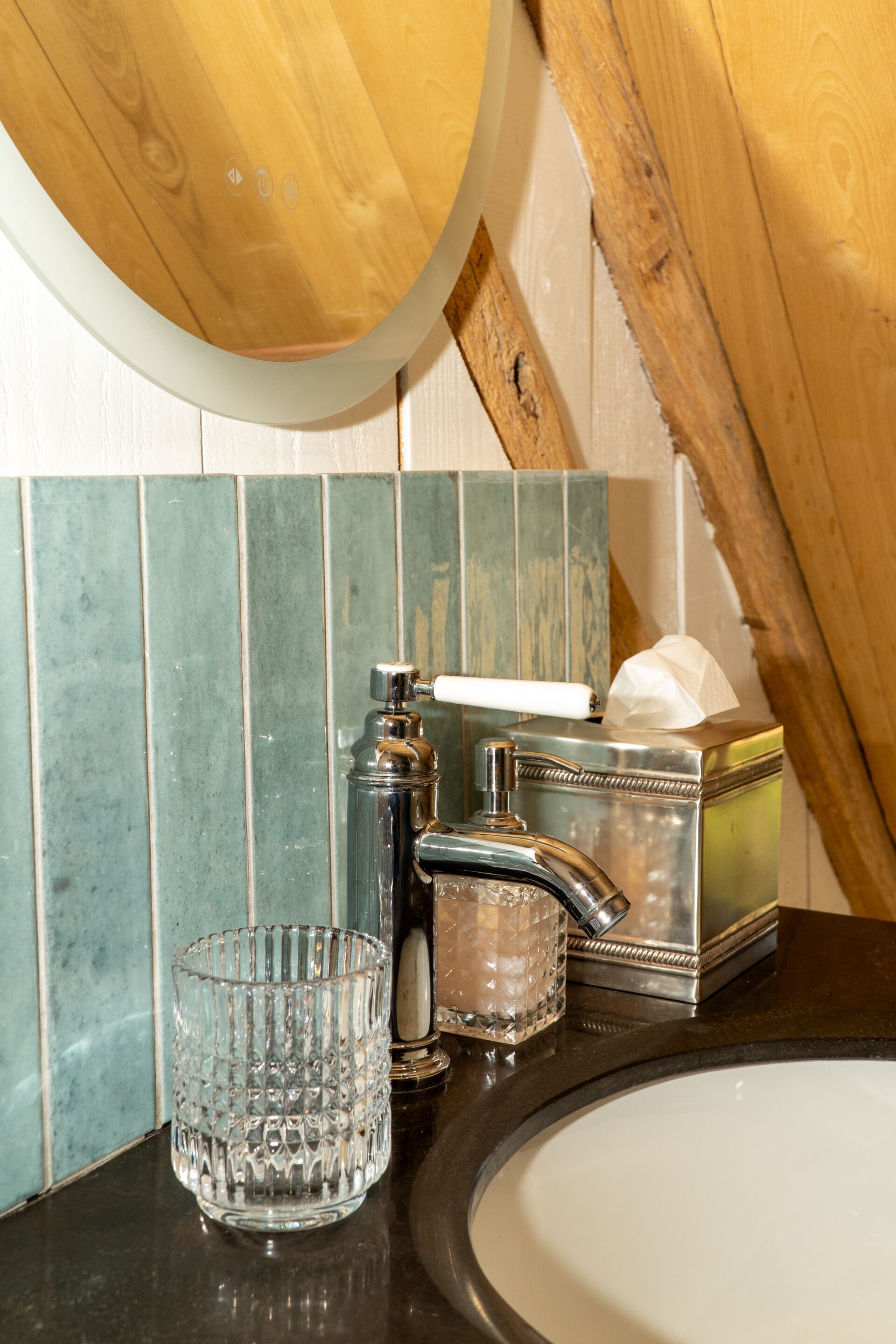 Een badkamer met een houten plafond, een wastafel, een glazen vaas en een zakdoos.