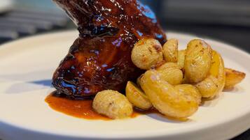 A plate with a glazed meat dish and roasted potatoes.