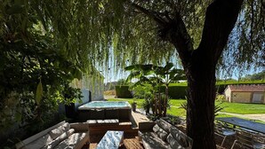 An outdoor seating area with sofas and a hot tub, surrounded by trees and a lawn. - RELAI VALDIEU (Courgeon)