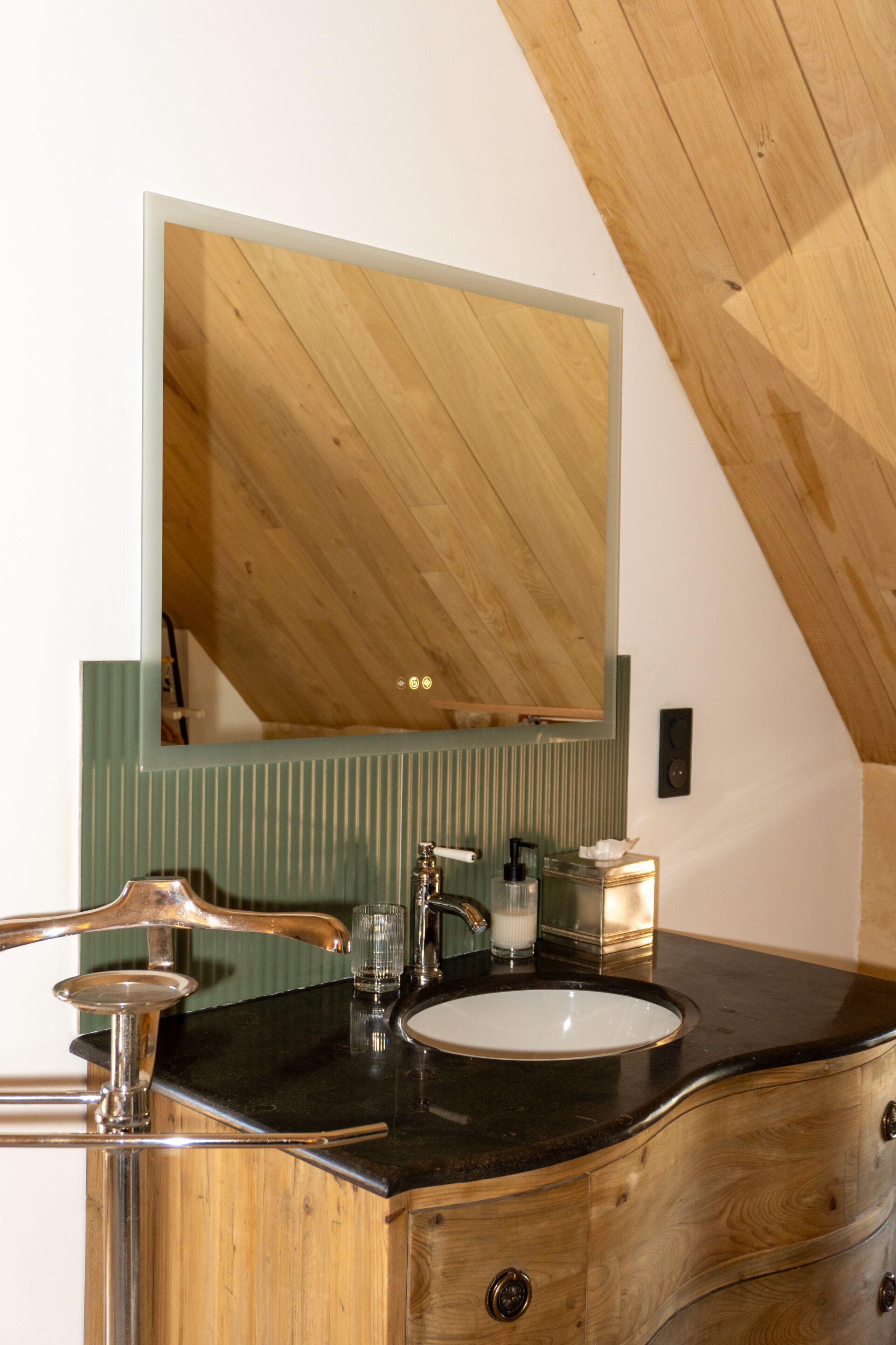 A bathroom with a wooden vanity, a sink, a mirror, and a towel dispenser.