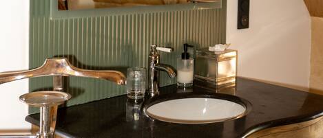 A bathroom with a wooden vanity, a sink, a mirror, and a towel dispenser.