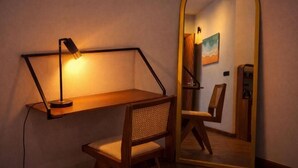 Quarto com escrivaninha, cadeira e espelho com moldura dourada.