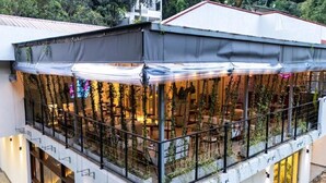 Um edifício com vários níveis, áreas de estar ao ar livre, guarda-corpos e uma seção coberta com plantas.
